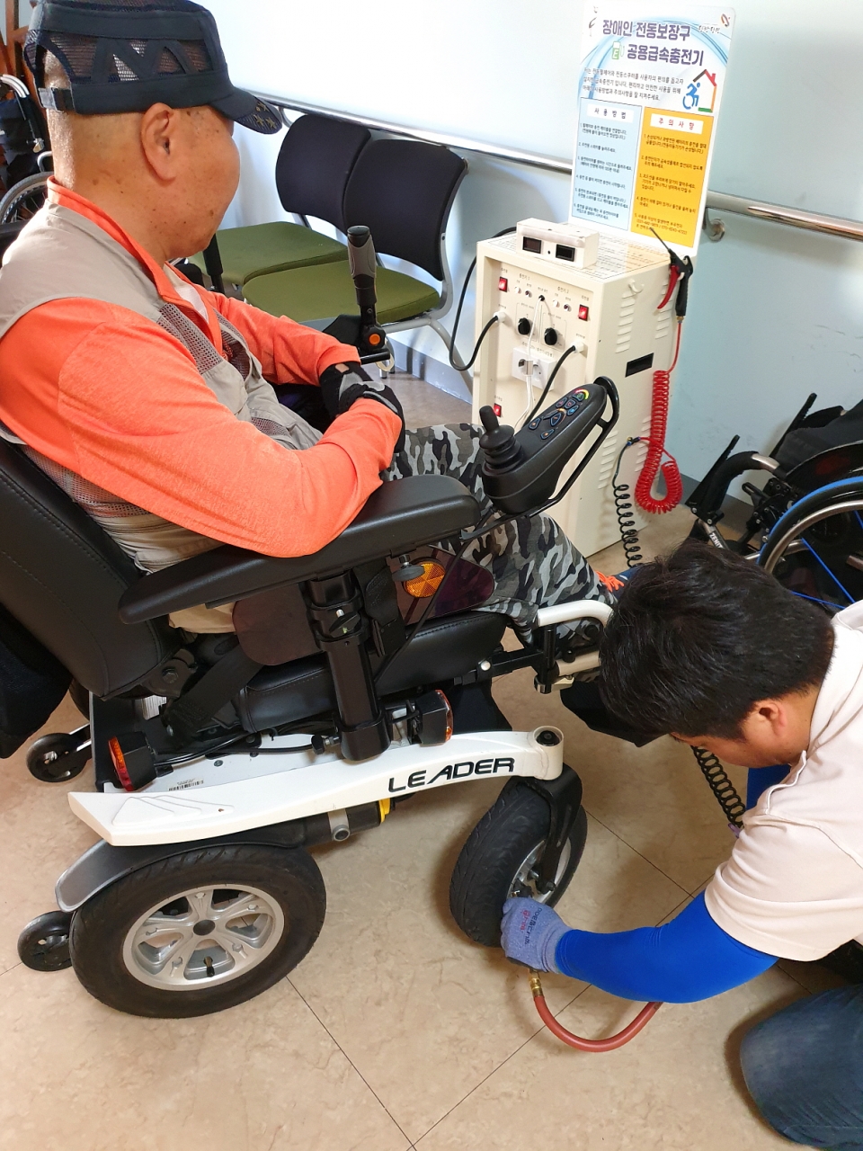 장애인복지관 내 장애인전동보장구 공용충전기에서 휠체어에 바람을 넣고 있는 모습