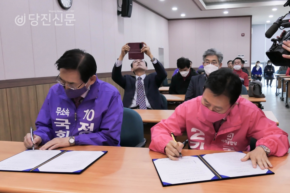 무소속 정용선 후보와 미래통합당 김동완 후보가 협약서에 서명을 하고 있다.
